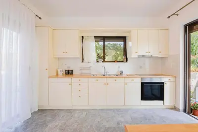 a kitchen with white cabinets and a sink and a window at Villa Bella Natura in Afantou