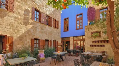 a patio with tables and chairs and a building at Kókkini Porta Rossa in Rhodes Town