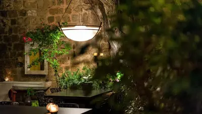 a room with a table with a light and plants at Kókkini Porta Rossa in Rhodes Town