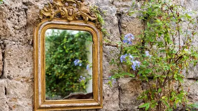 a mirror on a stone wall with purple flowers at Kókkini Porta Rossa in Rhodes Town