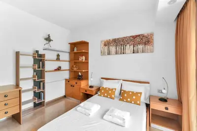 a bedroom with a white bed and a wooden desk at Veranna Lux Apartment in Ialyssos