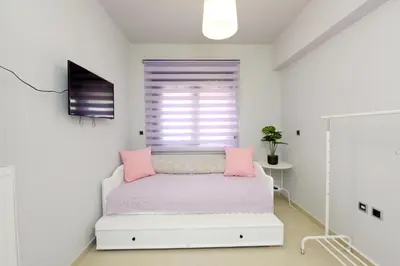 a white bedroom with a bed with pink pillows at Theros Lux Apartment in Émbonas