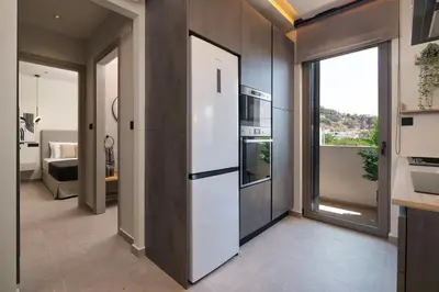 a kitchen with a refrigerator and a living room at Masarou Suites in Afantou