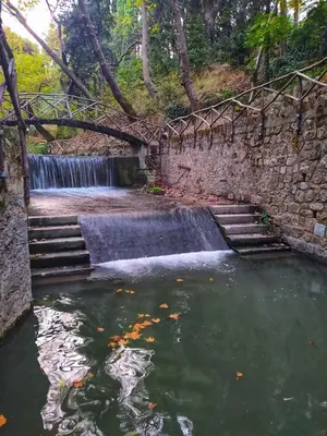 a pond with a waterfall in front of a stone wall at Golden Sand 2 in Ialyssos