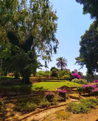 a park with flowers and trees on a sunny day at Golden Sand 2 in Ialyssos