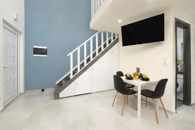 a dining room with a table with chairs and a tv at Golden Sand 2 in Ialyssos