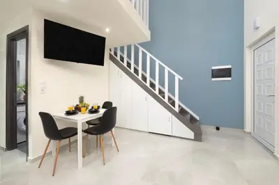 a dining room with a table and chairs and a staircase at Golden Sand 3 in Ialyssos