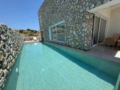 a swimming pool in front of a stone building at Delfinia Luxury Residence in Kolimbia