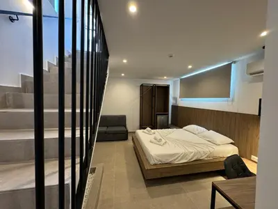 a bedroom with a bed and a couch and stairs at Delfinia Luxury Residence in Kolimbia