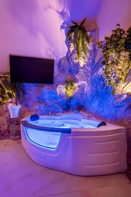 a hot tub in a room with a rock wall at Ethnic Cave Suite in Rhodes Town