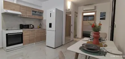 a kitchen with a table and a white refrigerator at Villa Marina apartment Jasmine in Ixia