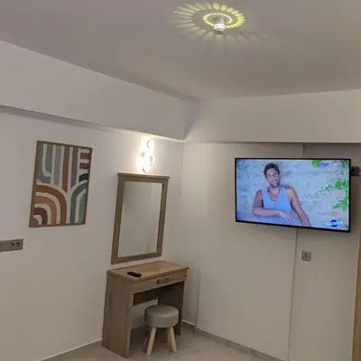 a room with a tv on a wall with a mirror at Villa Marina apartment Jasmine in Ixia