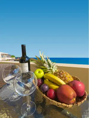 a basket of fruit on a table with wine glasses at Al Mare Villas in Kiotari