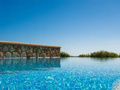 a pool of water with trees in the background at Al Mare Villas in Kiotari