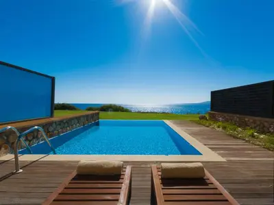 a swimming pool with a screen on a wooden deck at Al Mare Villas in Kiotari