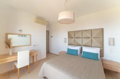 a bedroom with a bed with blue pillows and a desk at Al Mare Villas in Kiotari