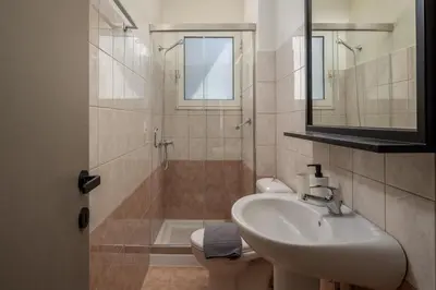 a bathroom with a sink and a toilet and a mirror at Colori Di Maria in Afantou