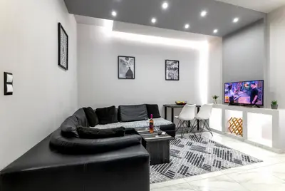 a living room with a black leather couch and a table at Reborn Luxury Apartments in Rhodes Town