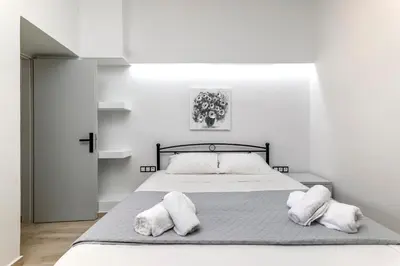 a white bedroom with a bed with two white pillows at Reborn Luxury Apartments in Rhodes Town