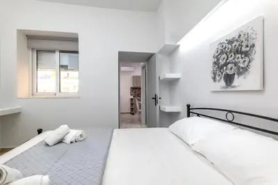 a white bedroom with a bed and a window at Reborn Luxury Apartments in Rhodes Town