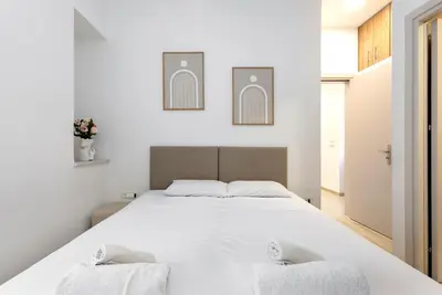 a bedroom with a large white bed with two towels at Reborn Luxury Apartments in Rhodes Town