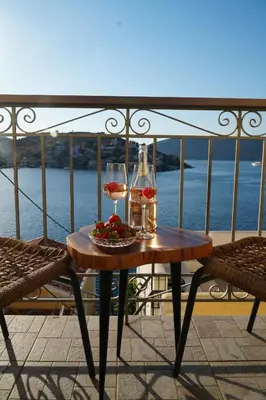 a table with two glasses of wine on a balcony at Bella Vista in Symi