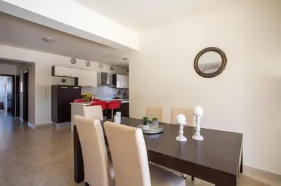 a dining room and kitchen with a table and chairs at Villa Frady in Kolimbia
