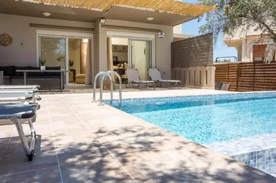 a swimming pool with chairs and a house at Villa Frady in Kolimbia
