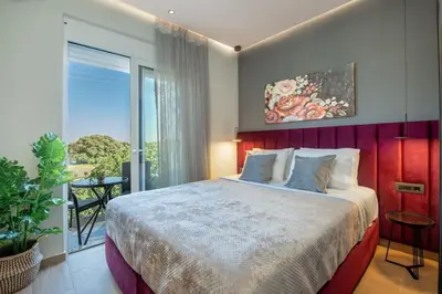 a bedroom with a large bed and a balcony at Santa Marina Luxury Apartments #3 in Asgourou