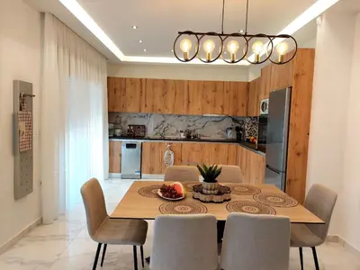 a dining room table with chairs and a kitchen at Alexa Luxury Suites in Afantou
