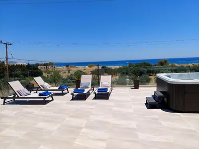 a row of lounge chairs on a patio with a hot tub at Alexa Luxury Suites in Afantou