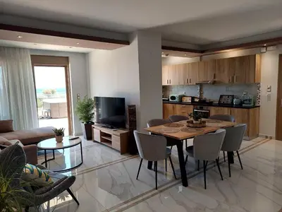 a living room with a dining table and a kitchen at Alexa Luxury Suites in Afantou