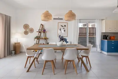 a dining room with a wooden table and white chairs at Bougan Villa in Lardos