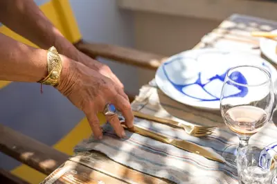 a person reaching for a glass of wine on a table at kalosymi house,Symi in Symi