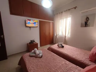 a bedroom with two beds and a tv on the wall at Anastasia's Cozy Retreat in Ialyssos