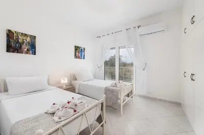 a white bedroom with two beds and a window at Nimo Paradise Estate in Paradeísion