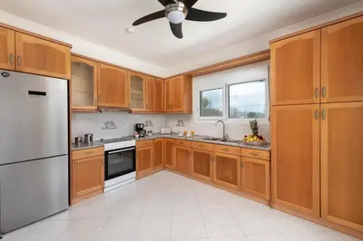 a kitchen with wooden cabinets and a ceiling fan at Nimo Paradise Estate in Paradeísion