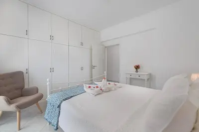 a white bedroom with a bed and a chair at Nimo Paradise Estate in Paradeísion