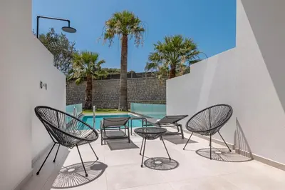 a patio with chairs and a table and a pool at Tota Suites in Afantou