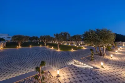 an empty courtyard with trees and lights at night at Tota Suites in Afantou