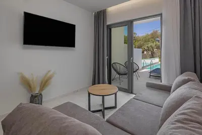 a living room with a couch and a table and a tv at Tota Suites in Afantou