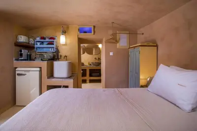 a bedroom with a large bed and a kitchen at kalosymi studio, Symi in Symi