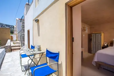 a patio with blue chairs and a table on a balcony at kalosymi studio, Symi in Symi