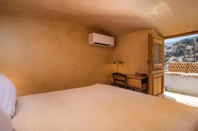 a bedroom with a bed and a window and a desk at kalosymi studio, Symi in Symi