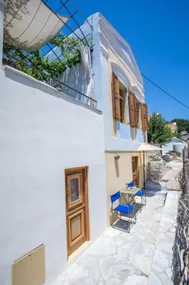 a white house with blue chairs and a table at kalosymi studio, Symi in Symi