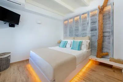 a white bedroom with a bed and a window at Lindos Allure Villa with Jacuzzi and Acropolis view!!! in Líndos