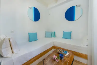 a white bed with blue pillows and a table at Lindos Allure Villa with Jacuzzi and Acropolis view!!! in Líndos