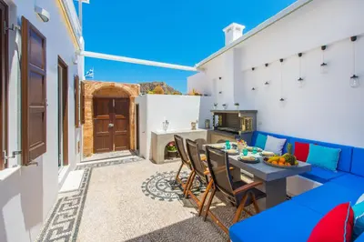 a patio with a blue couch and a table at Lindos Allure Villa with Jacuzzi and Acropolis view!!! in Líndos