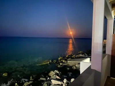 a view of the ocean at night with a light in the water at Diamond Seaview Stegna in Archangelos