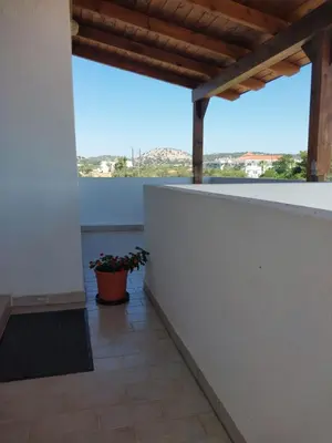 a balcony with a white wall and a potted plant at Marias Apartment in Kolimbia